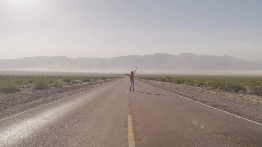 A teenage girl turns in circles in the middle of a street