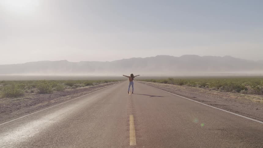 A woman is standing in the middle of the road