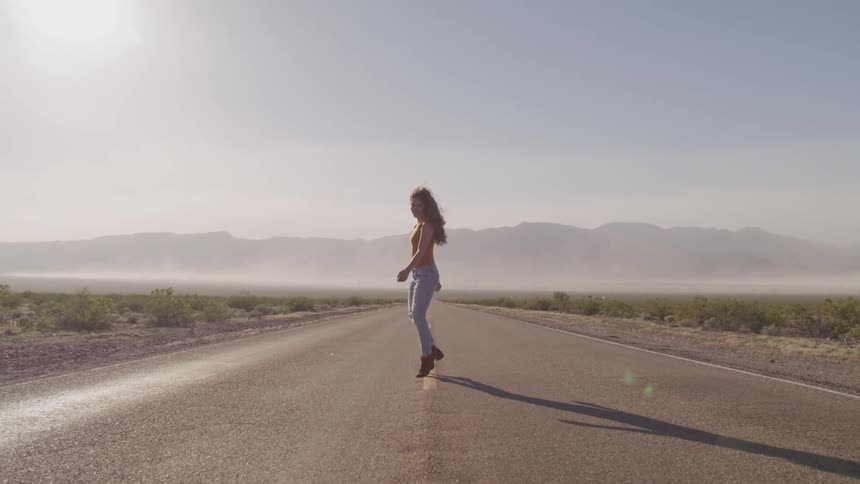 A woman is walking on a road in a rural area