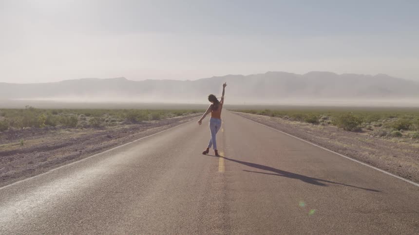 A woman is standing outdoors in the middle of the road