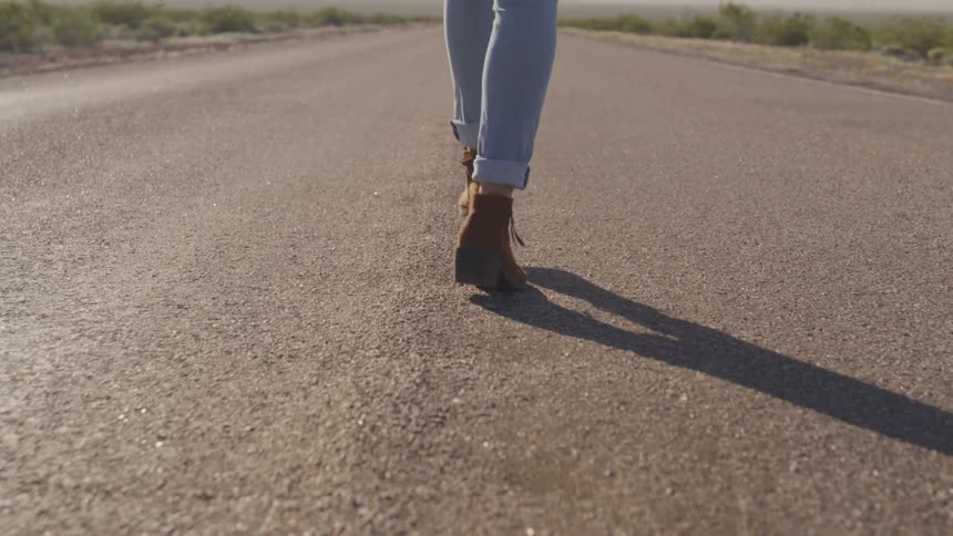 A woman is walking on a road in a rural area