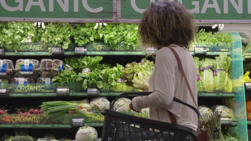 Young woman buying vegetables in a supermarket