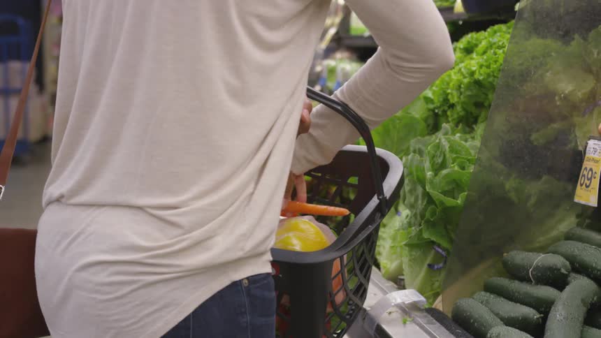 A woman picks vegetables at a grocery store