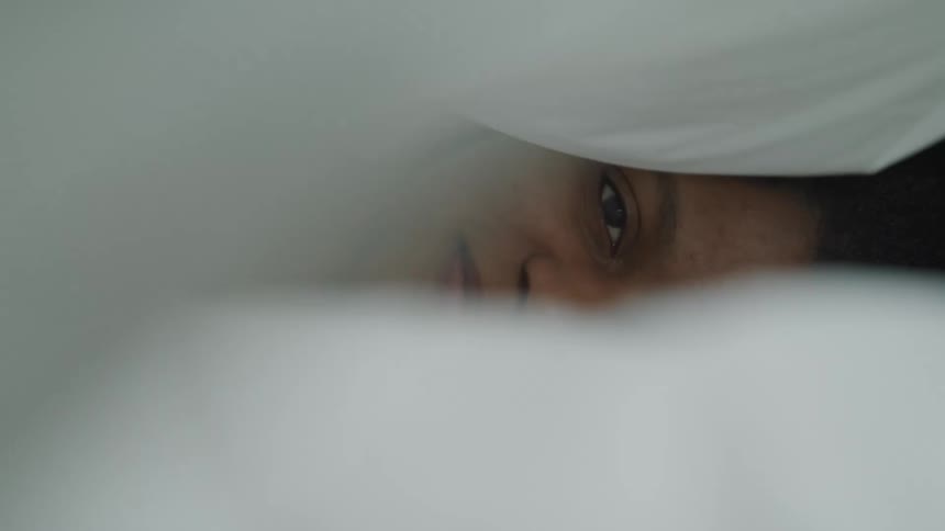 A woman laying in bed with a blanket over her