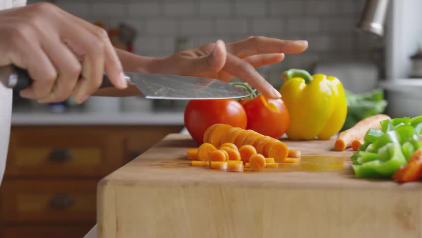 Slicing carrots with a chef knife then sliding next to sliced bell peppers