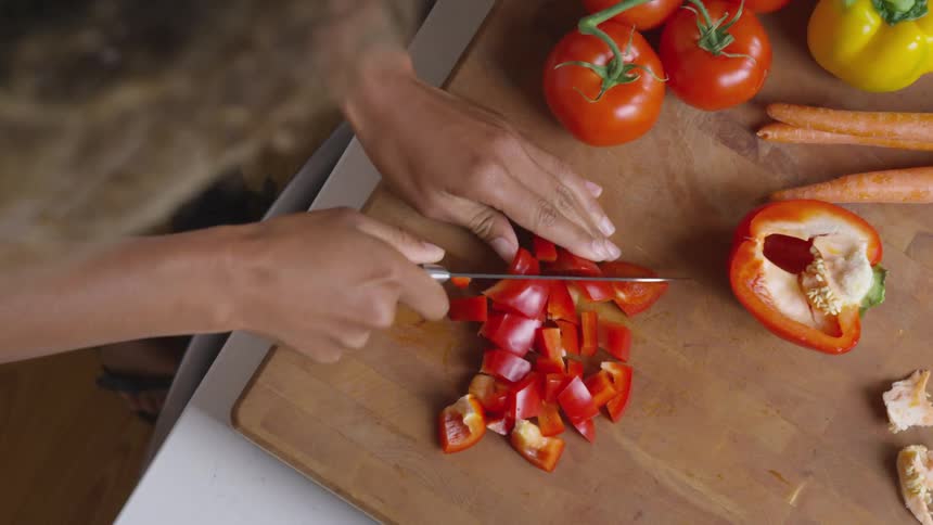 Woman chops vegetables on wooden chopping board