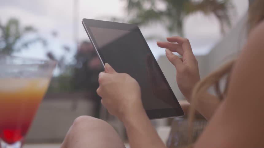 Woman sitting outside scrolls on tablet