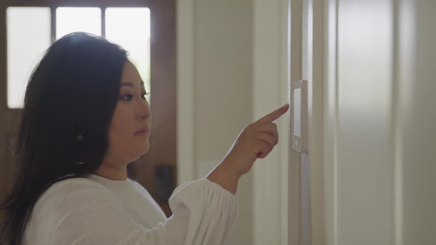 A woman sets an alarm in her home and heads to the door to leave