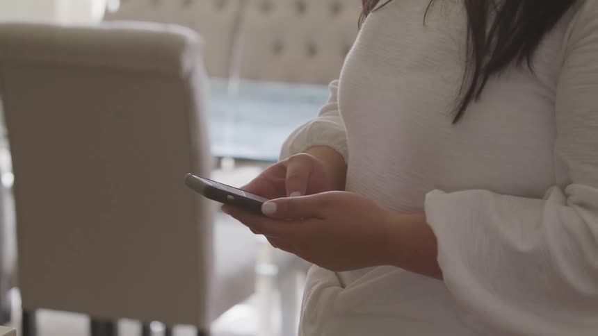 A woman scrolls on her cell phone