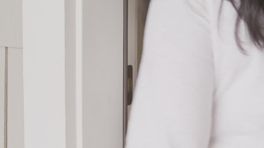 A woman enters a passcode into an electronic lock to unlock a door before entering