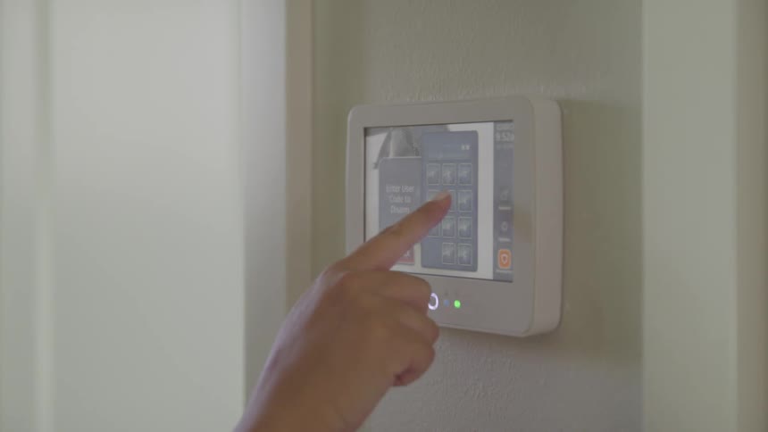 A woman adjusts the temperature in her house using a smart thermometer