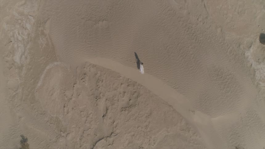 Person walks along across desert sand doon