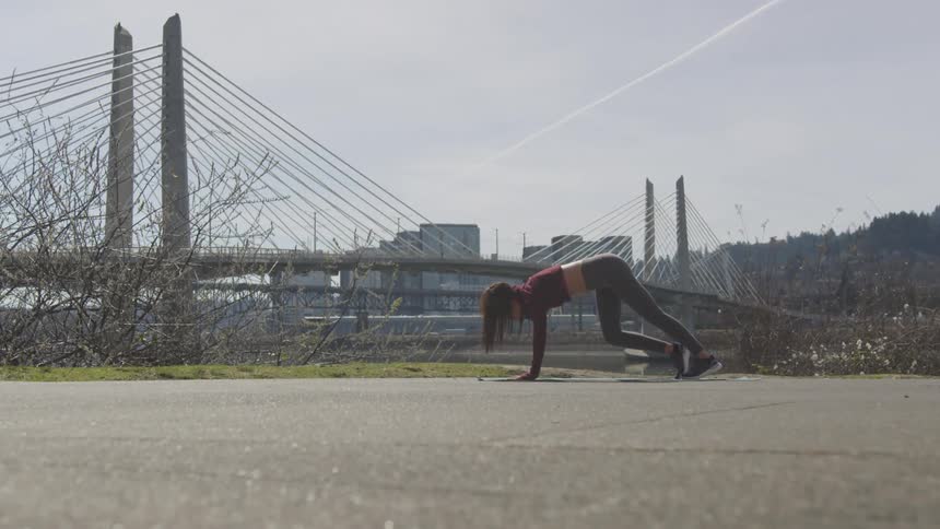A young woman stretching outside with the city skyline behind her