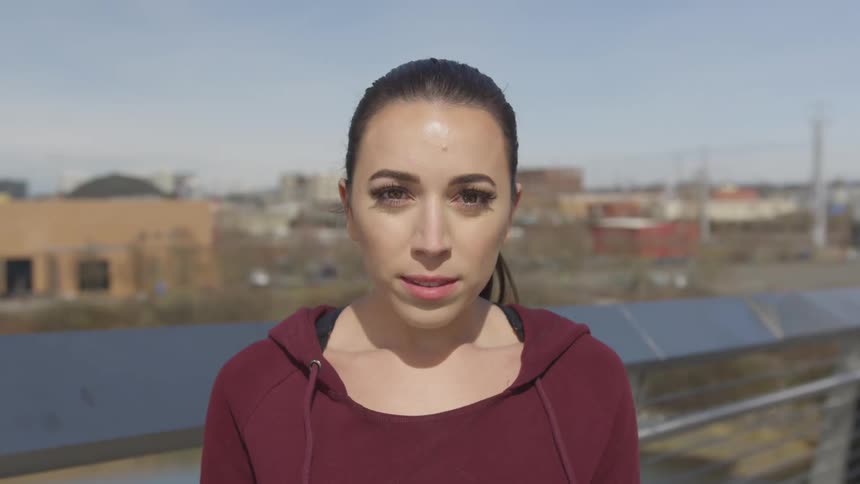 A young woman on a bridge with buildings behind her