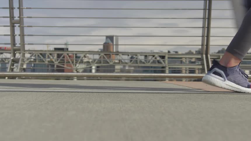Young woman wearing sports clothes jogging on a bridge near the city