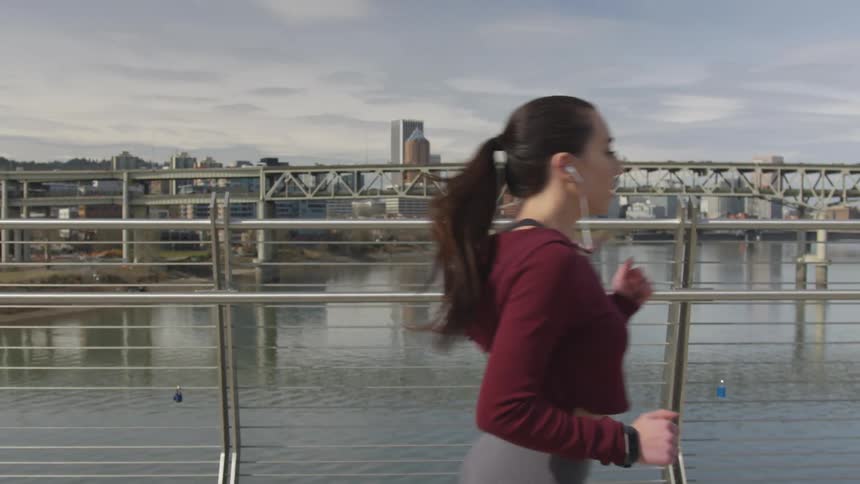 A woman is jogging outdoors near an ocean