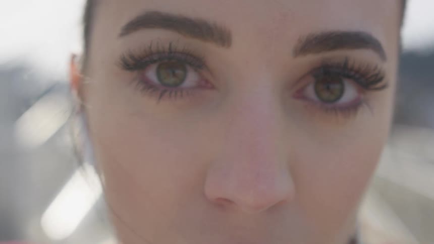A woman is outside wearing earbuds