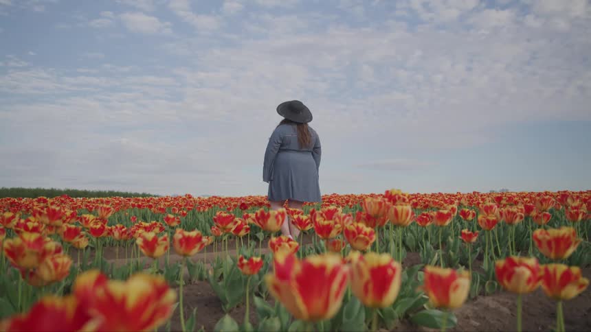 A woman is standing in a meadow of flowers