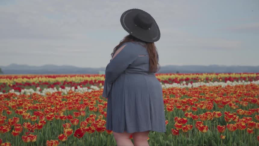 A woman is standing in a meadow of flowers