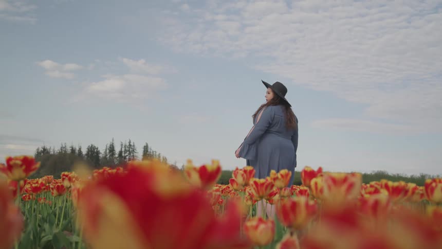A young woman walks through a field of flowers