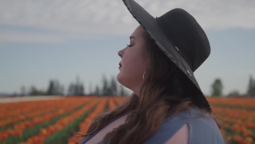 A woman is standing in a meadow of flowers