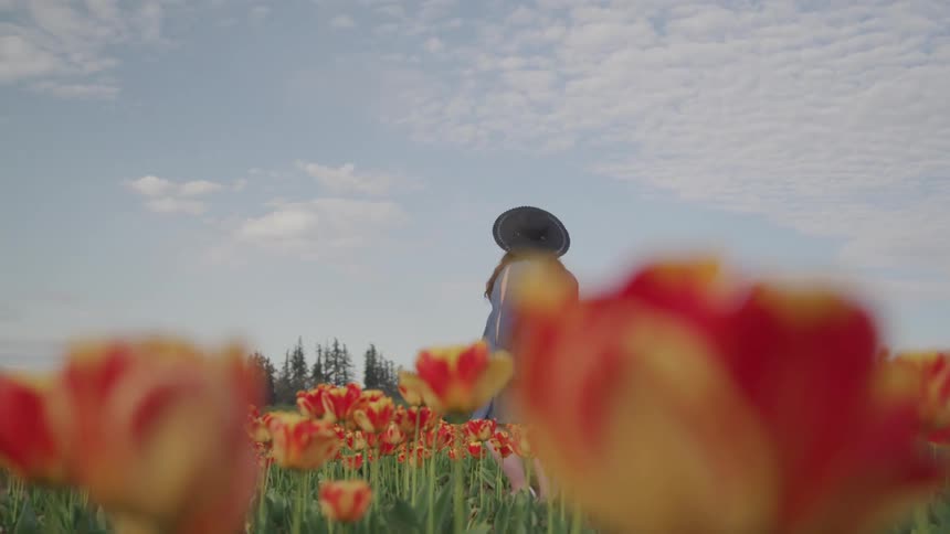 A woman walking through a field of flowers