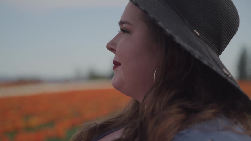A woman is standing outdoors while wearing a hat