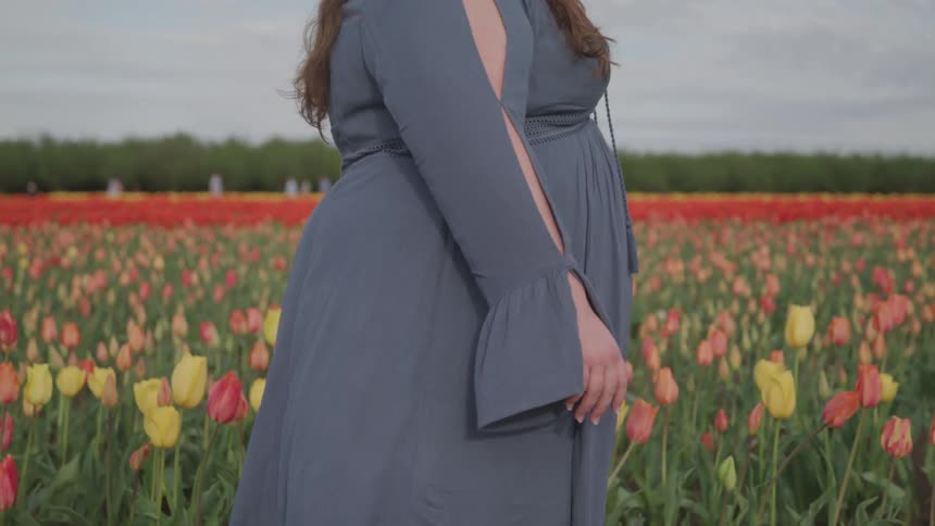 A woman walks through a field of flowers on a cloudy day