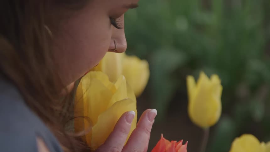 Woman smells yellow tulip