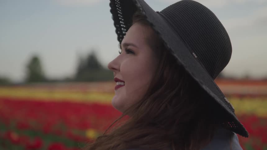 A woman is standing outdoors in a flower meadow