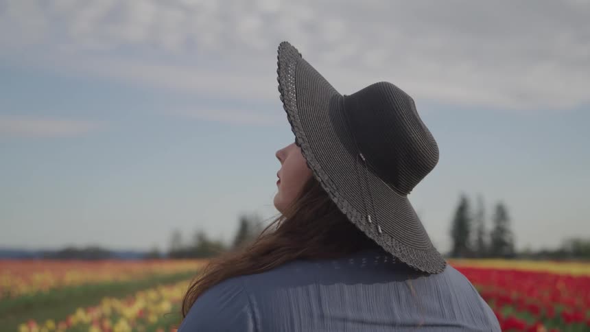 A woman is standing outdoors while wearing a sunhat