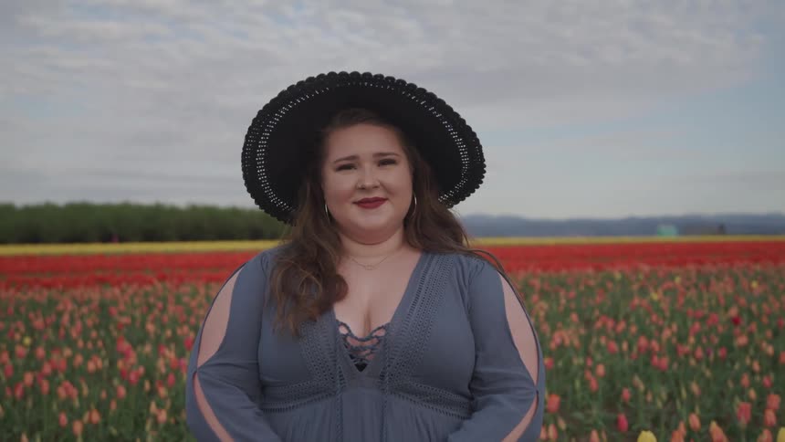 A woman standing in a field of flowers smiles