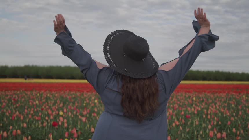 A woman is standing in a meadow of flowers