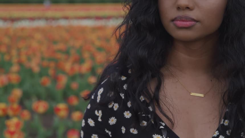 A woman is standing by a meadow of flowers