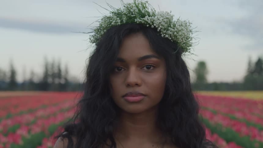A woman standing in a field of flowers with a flower crown on