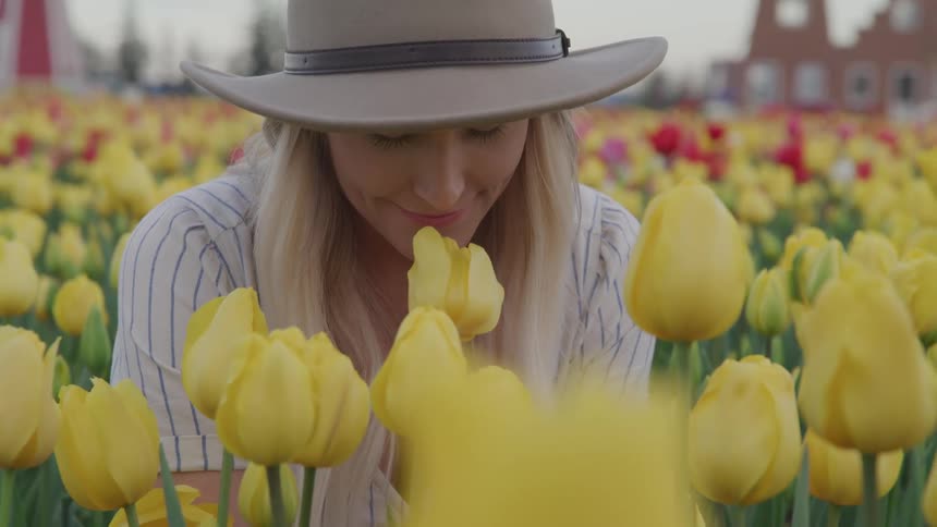 A woman sits in a field surrounded by tulips