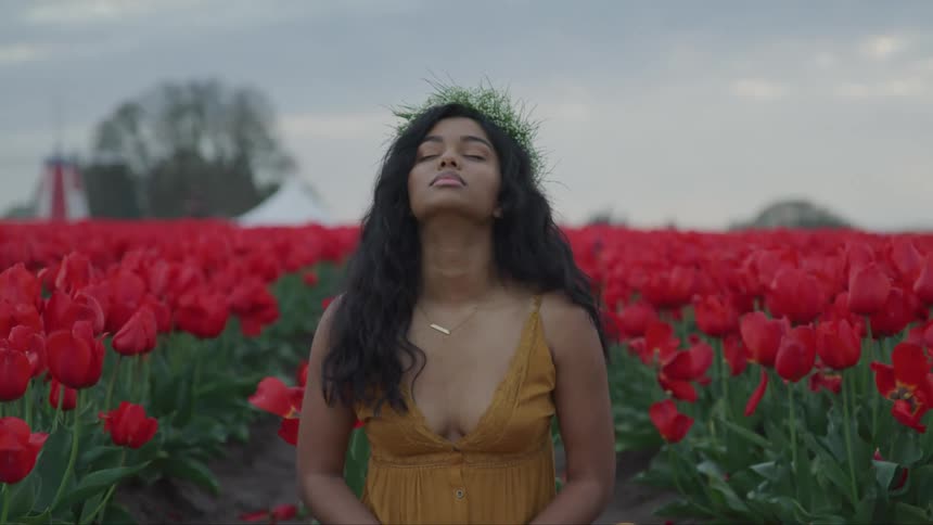 A teenage girl in a field of tulips meditates
