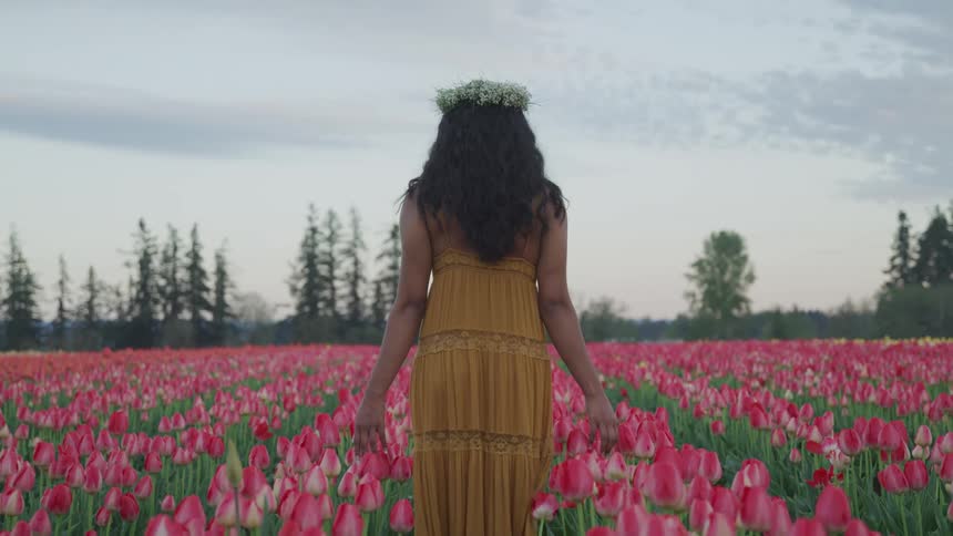 A woman walking through a field of flowers