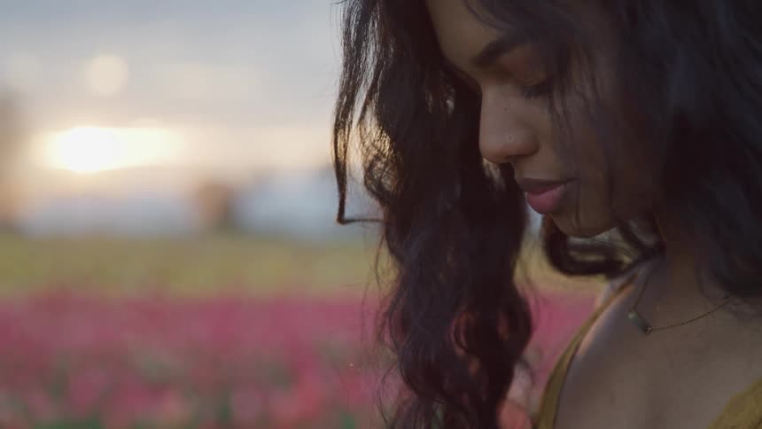 A woman is standing outdoors at dusk