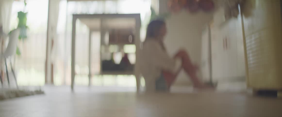 A woman sitting on the floor next to a table in the kitchen