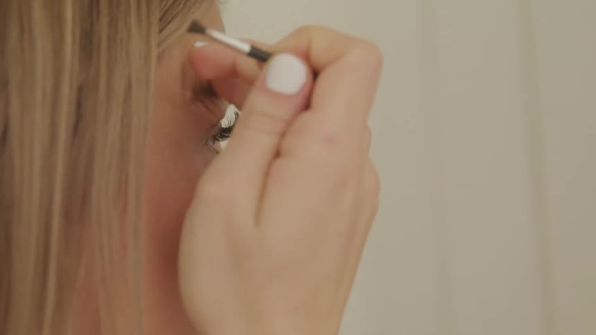 A woman uses a makeup brush on her eyebrows