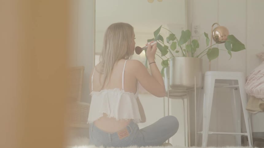 A woman is putting on makeup indoors