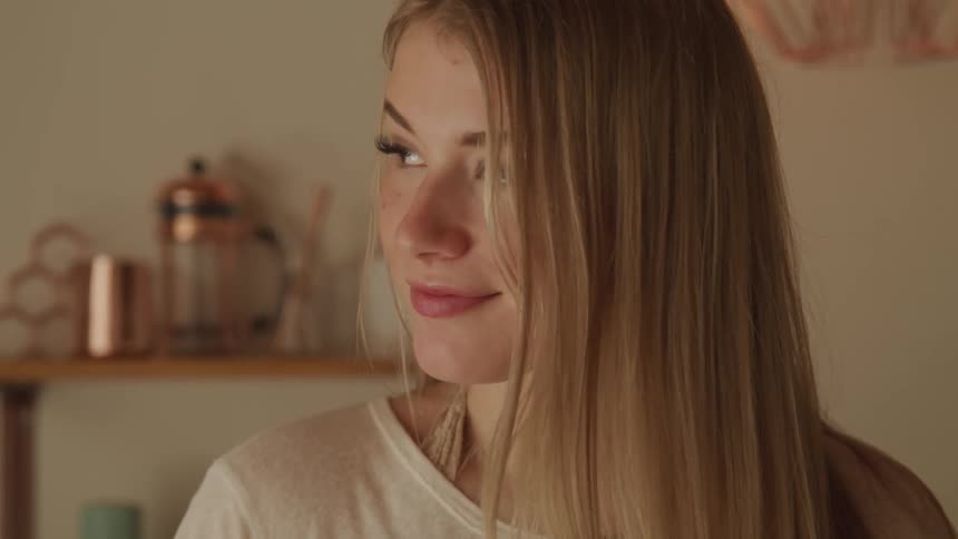 A woman is smiling inside a house