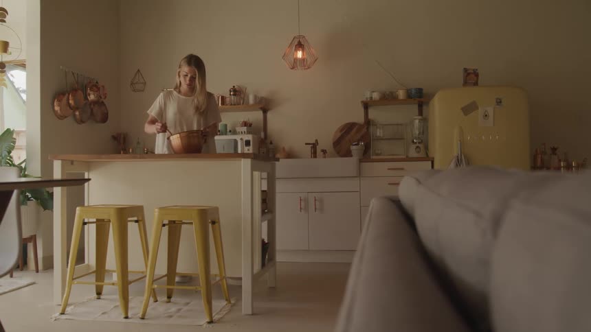 A woman stirring things in a bowl in a kitchen