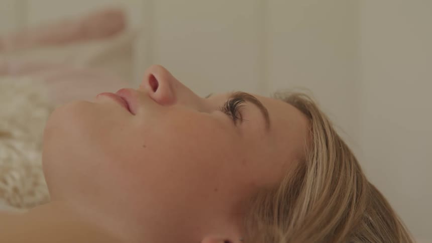 Side view of a blonde woman lying down on bed