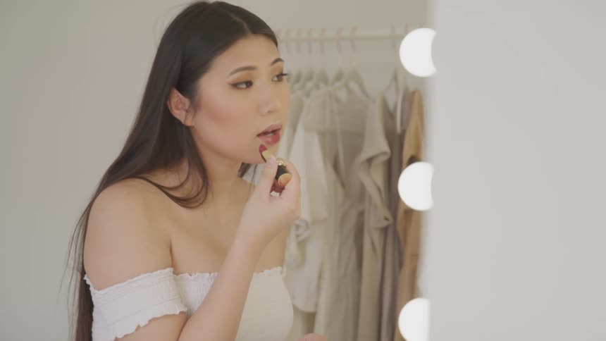 A teenage girl putting lipstick on