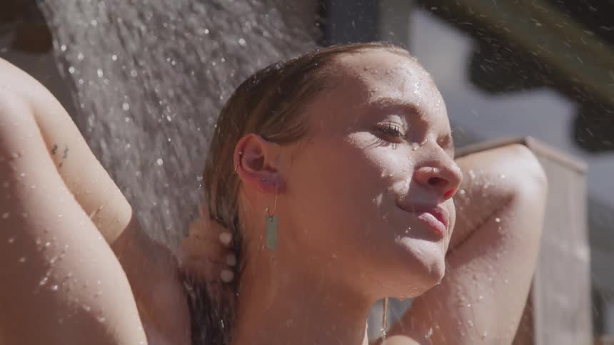 A woman is washing outside in a shower