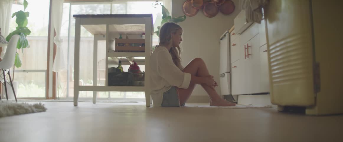 A female caucasian sitting on the kitchen floor