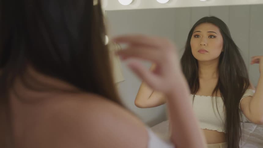Young woman looks at herself in a mirror in a changing room