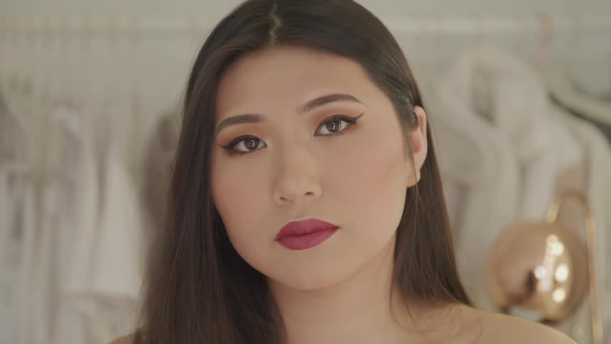 A woman with her makeup all done stands by bright lights